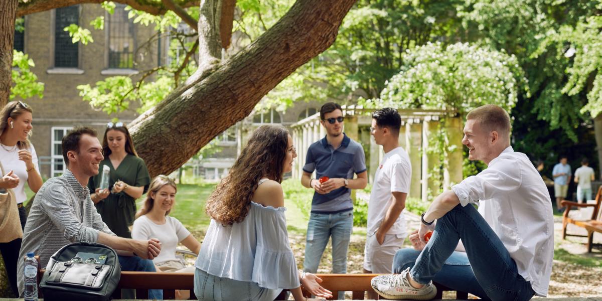 Studenten zitten op een zomerse dag in de tuin van de Faculteit der Rechtsgeleerdheid