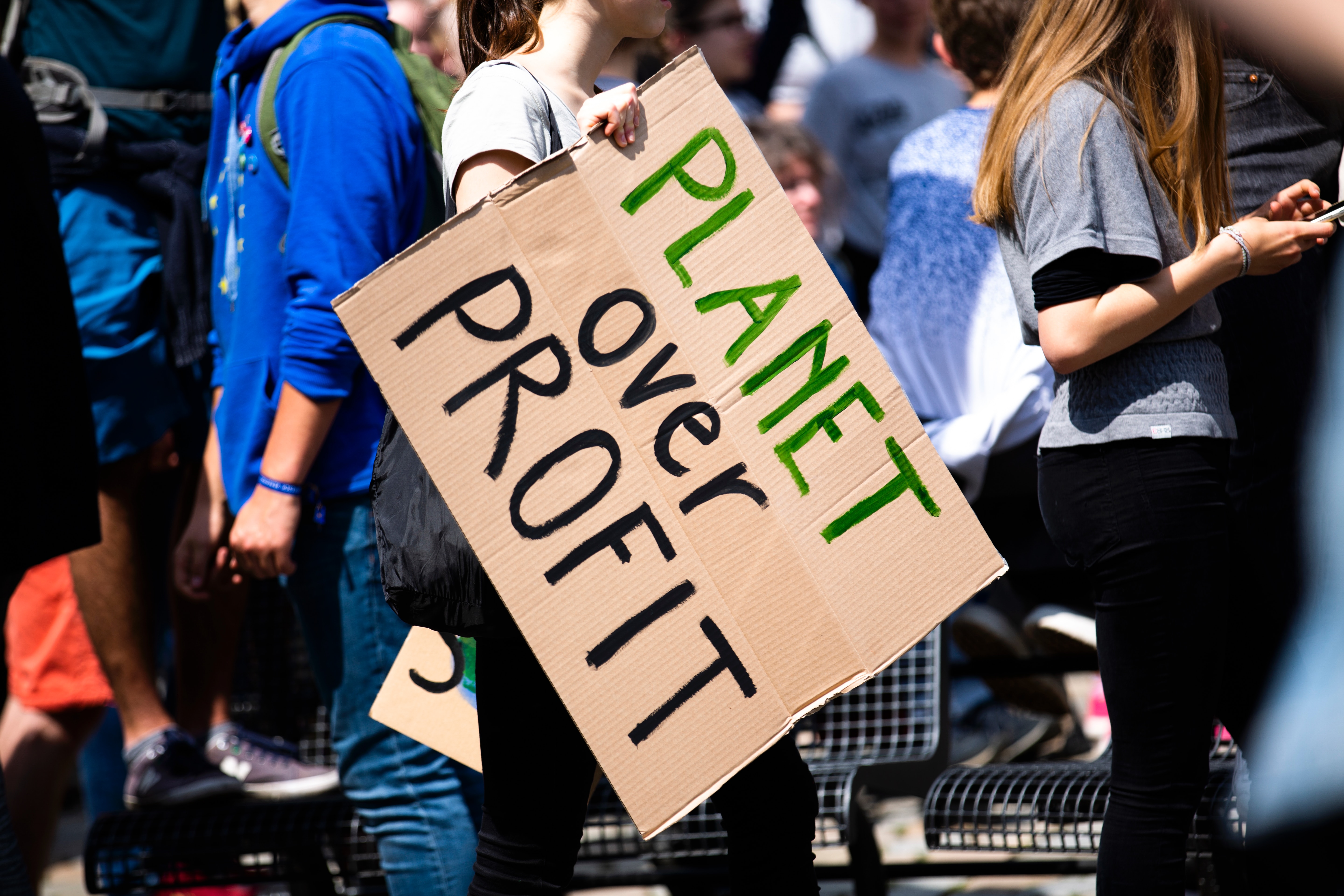 Lady holding a sign 'planet over profit'