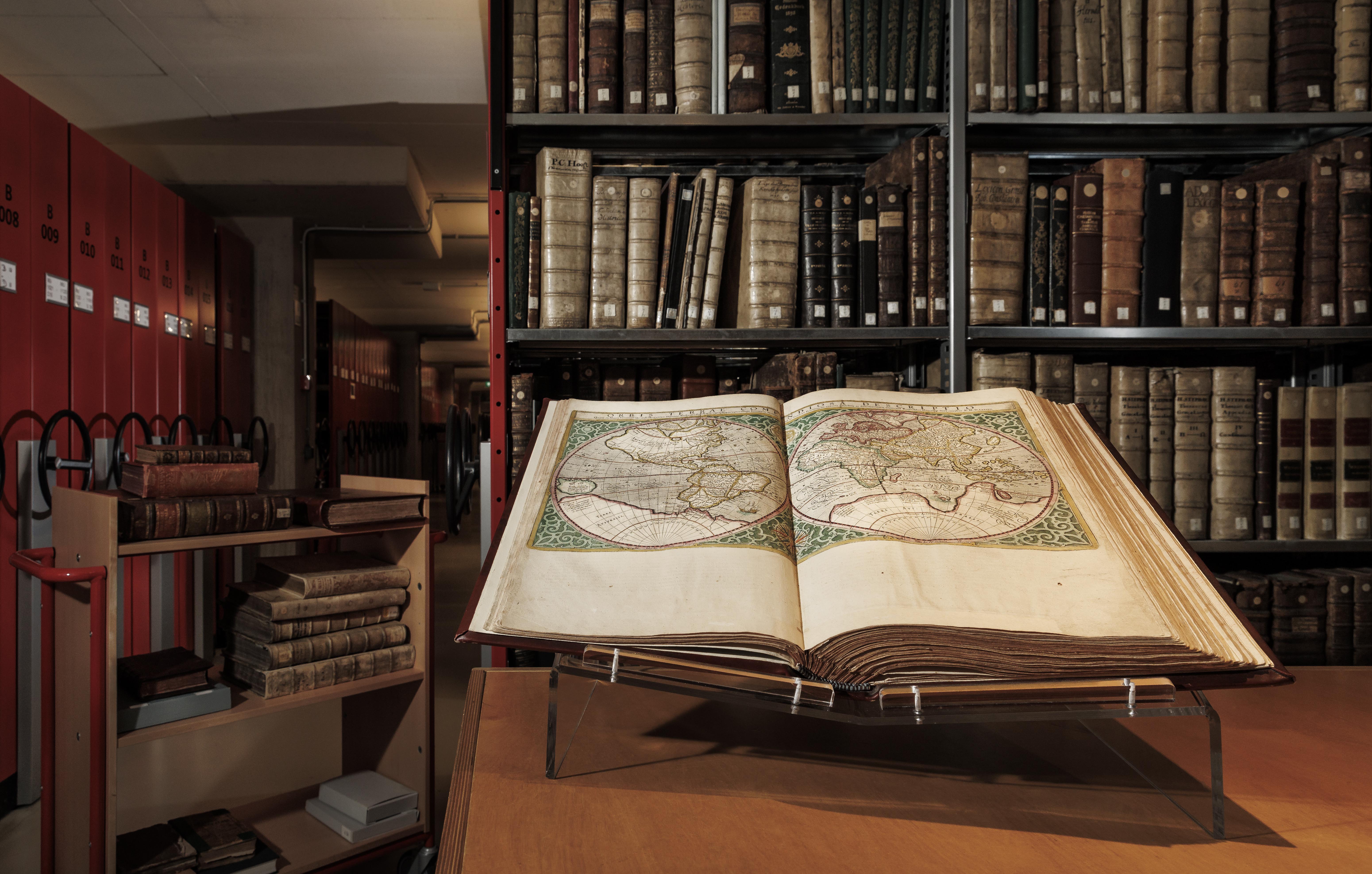 Library with antique books and open book with old map of the world