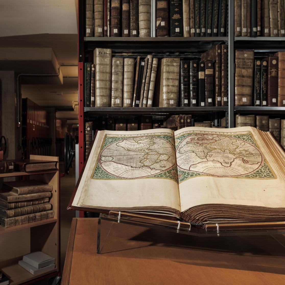 Library with antique books and open book with old map of the world