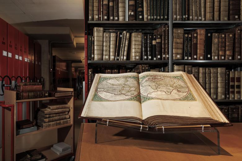 Library with antique books and open book with old map of the world